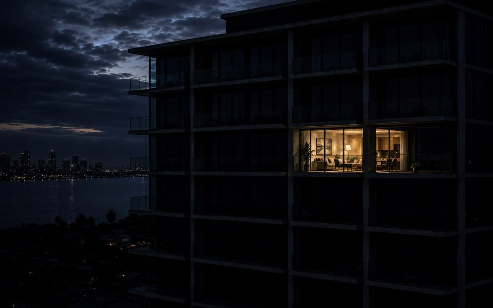 One lit apartment glowing in an otherwise dark high-rise at night